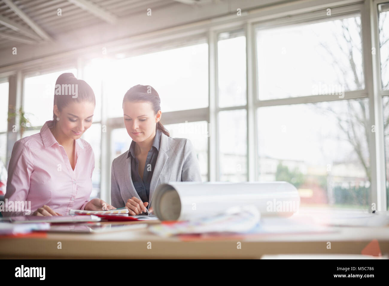 Femmina giovani architetti che lavorano insieme alla scrivania in ufficio Foto Stock