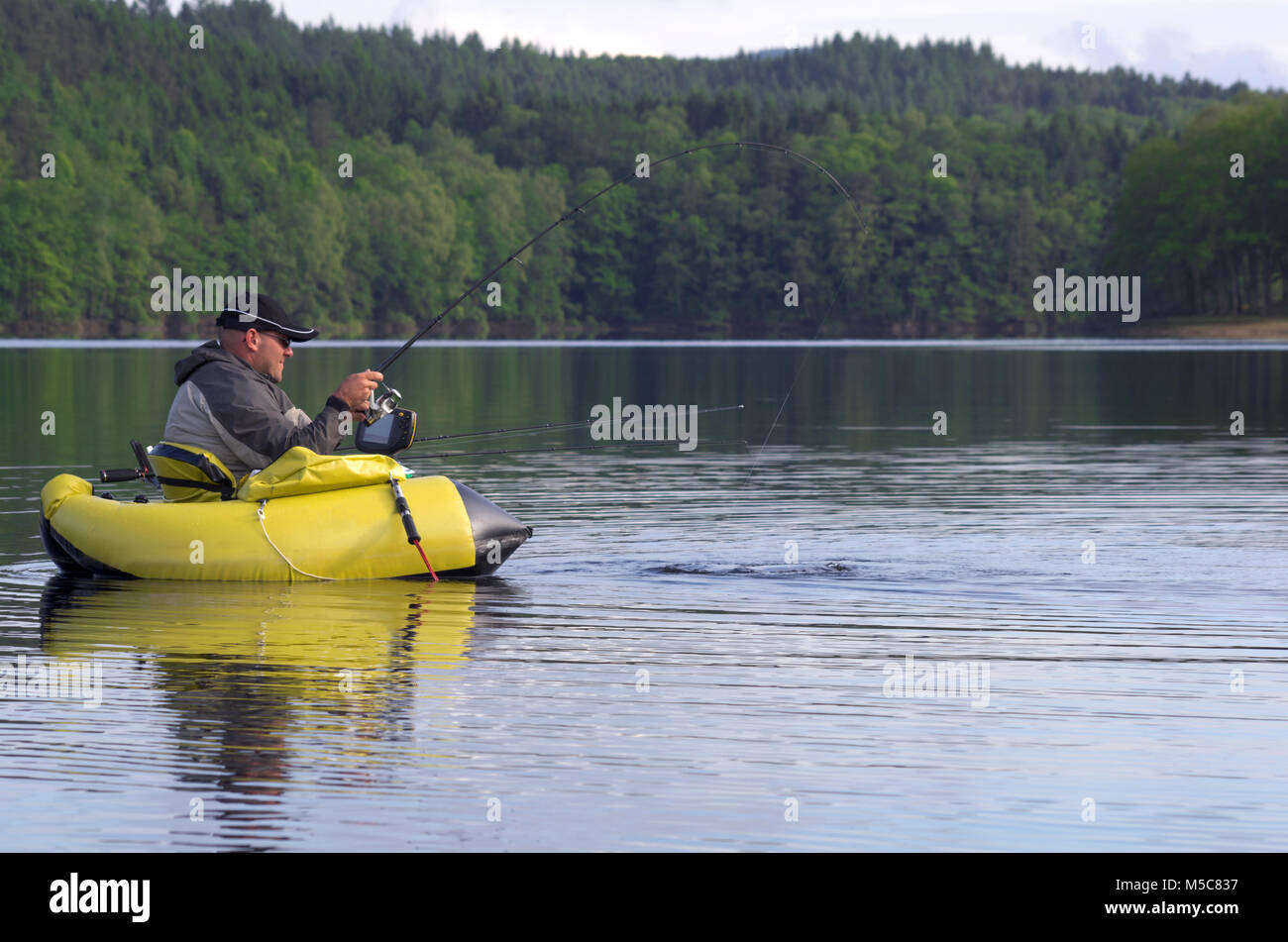 La pesca con un tubo galleggiante. L'uomo è seduto nella pesca barca  gonfiabile ed egli utilizzare pinne per spostarsi sull'acqua. fisherman  lotta contro un pike Foto stock - Alamy