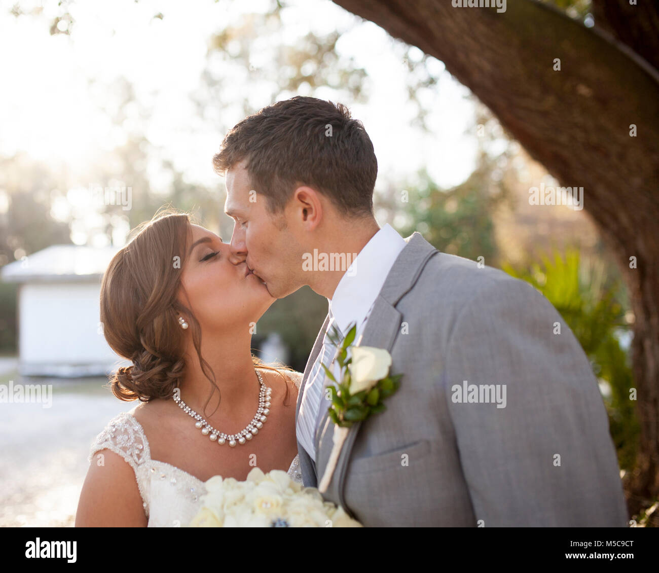 I giovani sposi kissing all'aperto Foto Stock