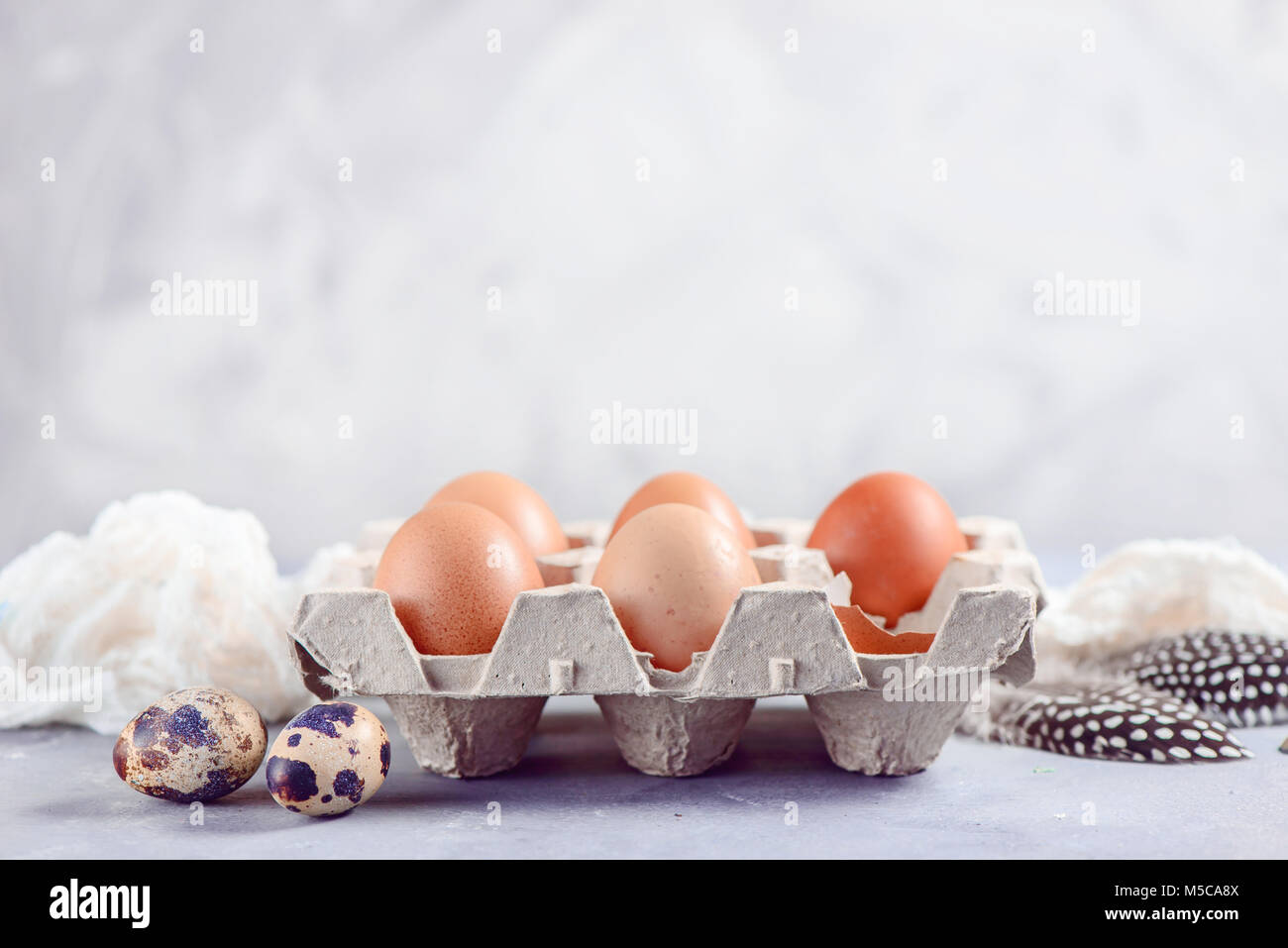 Uova di colore marrone a craft carton, pack su uno sfondo luminoso. Gli ingredienti freschi per la Pasqua di cottura. Tasto alto testata con copia spazio. Foto Stock