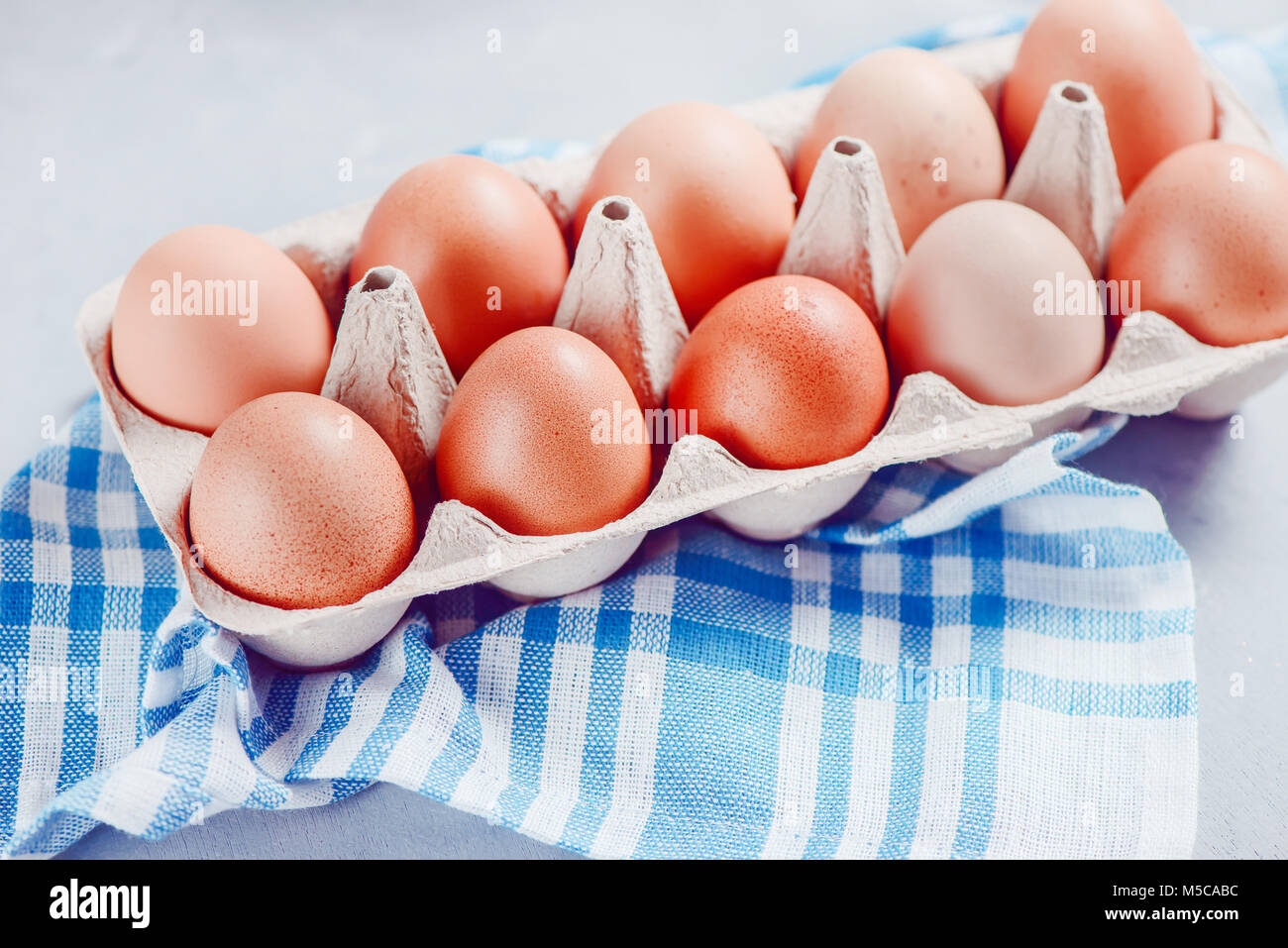Rosolare le uova in un foglio di carta cartone close-up su uno sfondo luminoso con napking blu. Preparazione per la cottura di Pasqua. Elevato La chiave dello sfondo con copia spazio. Foto Stock