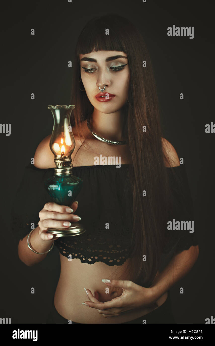 Dark bella donna che guarda la lanterna fiamma. Studio shot Foto Stock