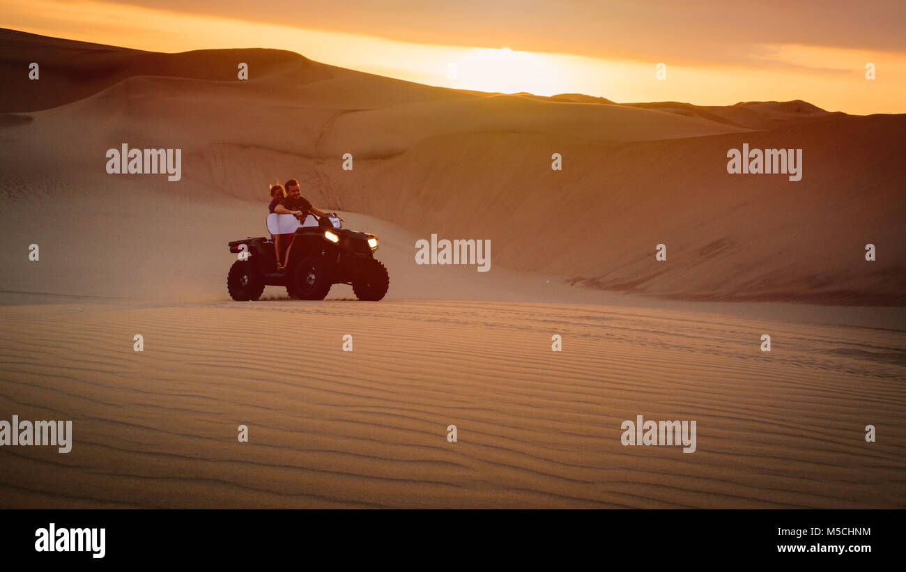 Paio di cavalcare un ATV che trasportano sabbia pensione in dune di Huacachina, Perù Foto Stock