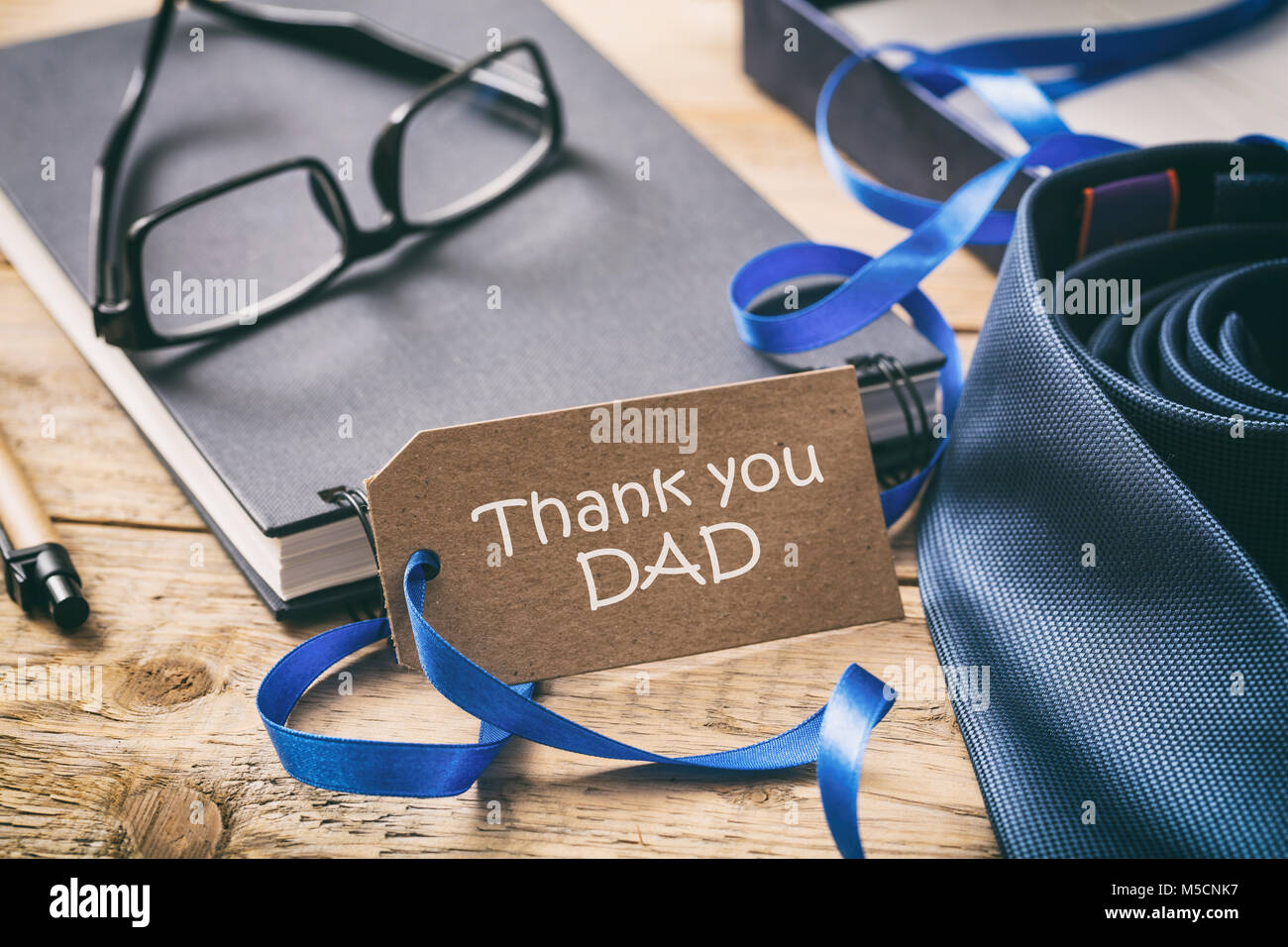 La festa del papà concetto. Cravatta blu, grazie papà scritto sul tag, ufficio sfondo scrivania Foto Stock