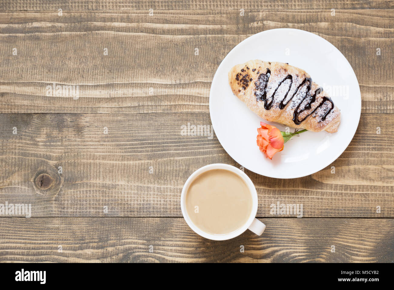 Delizioso pane appena sfornato croissant al cioccolato e caffè sulla tavola di legno. Vista dall'alto. Colazione femmina concetto. Copia dello spazio. Foto Stock