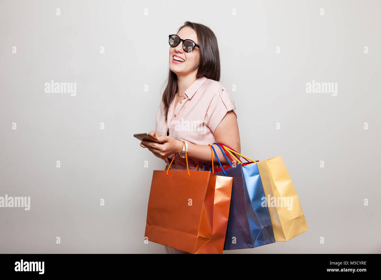 Ragazza ridere in trend utilizza internet store sul telefono cellulare per acquistare i prodotti e il negozio Foto Stock