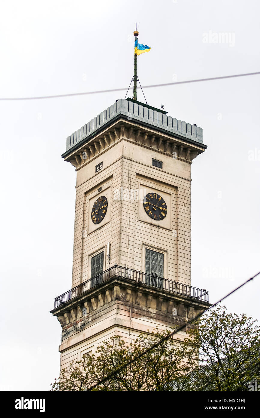 Lvov City Hall clock tower con faro a luce rotante e blu ucraino bandiera gialla contro il grigio cielo nuvoloso Foto Stock