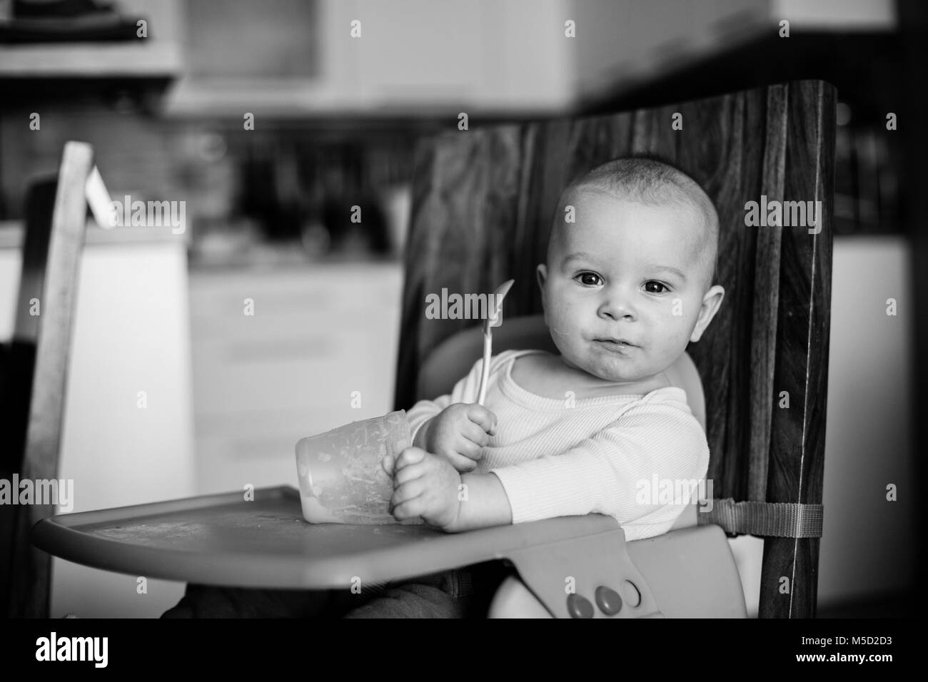 Little baby boy, mangiare purè di cibo per la prima volta nella sua vita Foto Stock