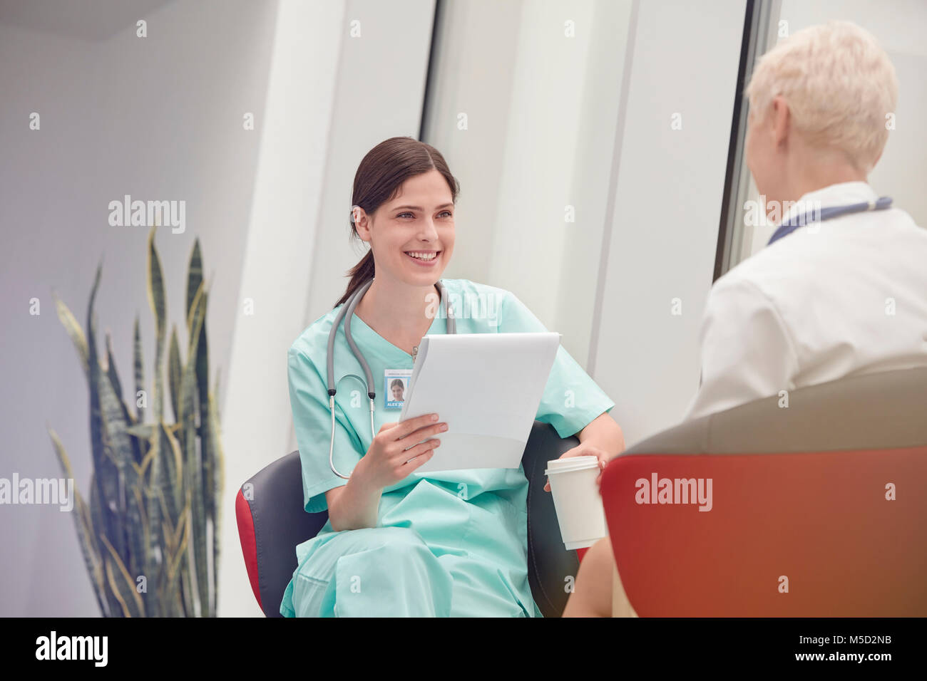 Donna sorridente con infermiere appunti a parlare con il medico in ospedale Foto Stock