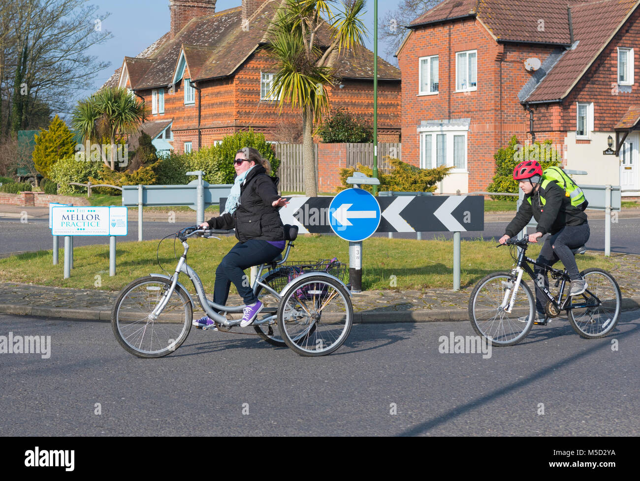 Donna in bicicletta su un triciclo a pedali bike con 3 ruote, attorno ad una piccola rotonda in Inghilterra, Regno Unito. Foto Stock