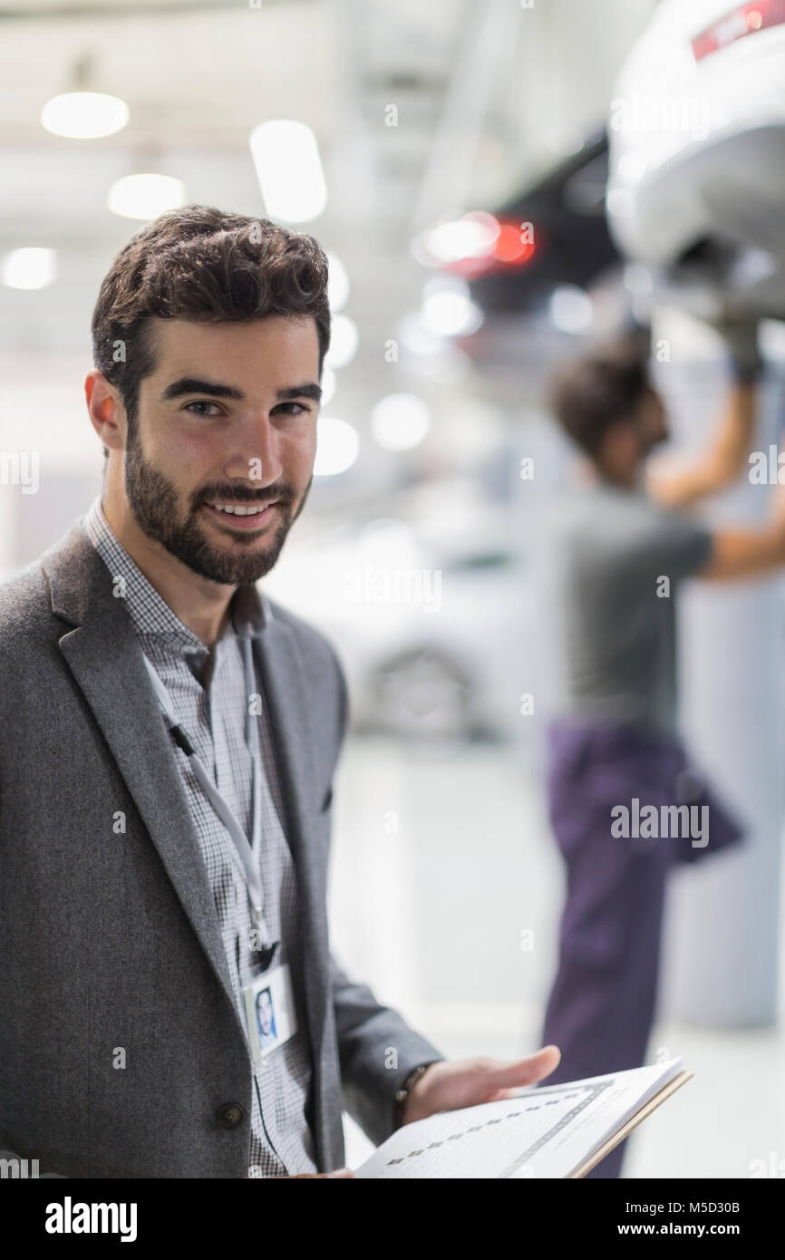 Ritratto sorridente, fiducioso uomo nel negozio di riparazioni auto Foto Stock
