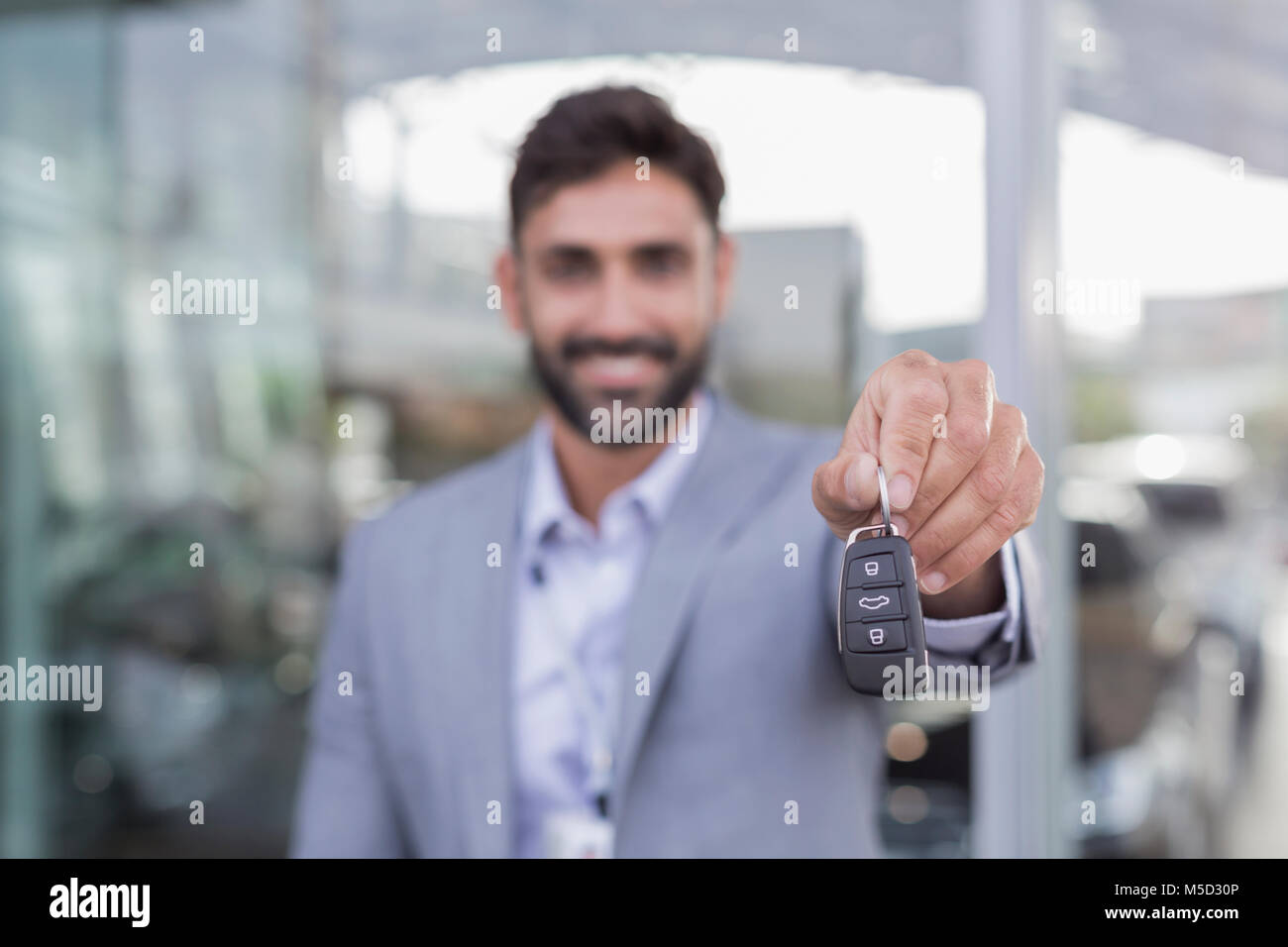 Ritratto sorridente, fiducioso venditore auto holding, che mostra nuove chiavi auto Foto Stock