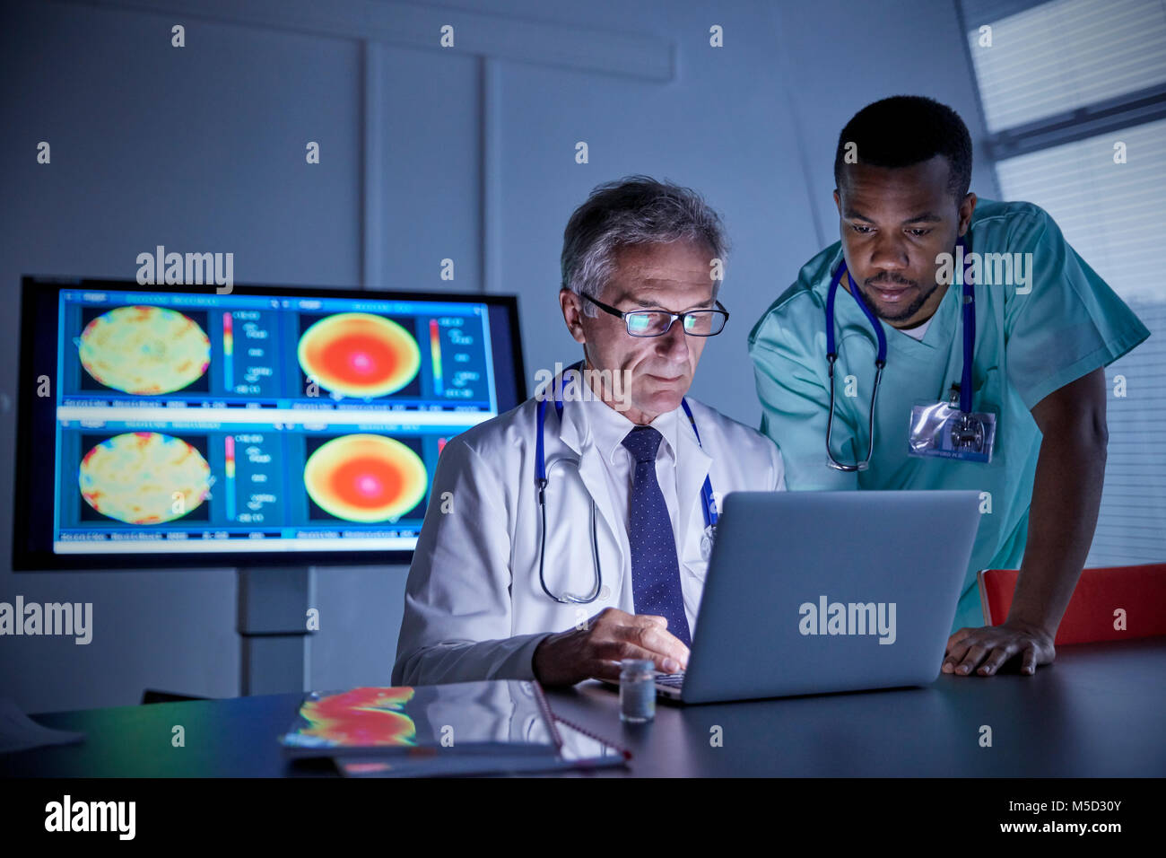 Maschio di chirurgo e medico che lavorano al computer portatile in ospedale sala conferenza Foto Stock