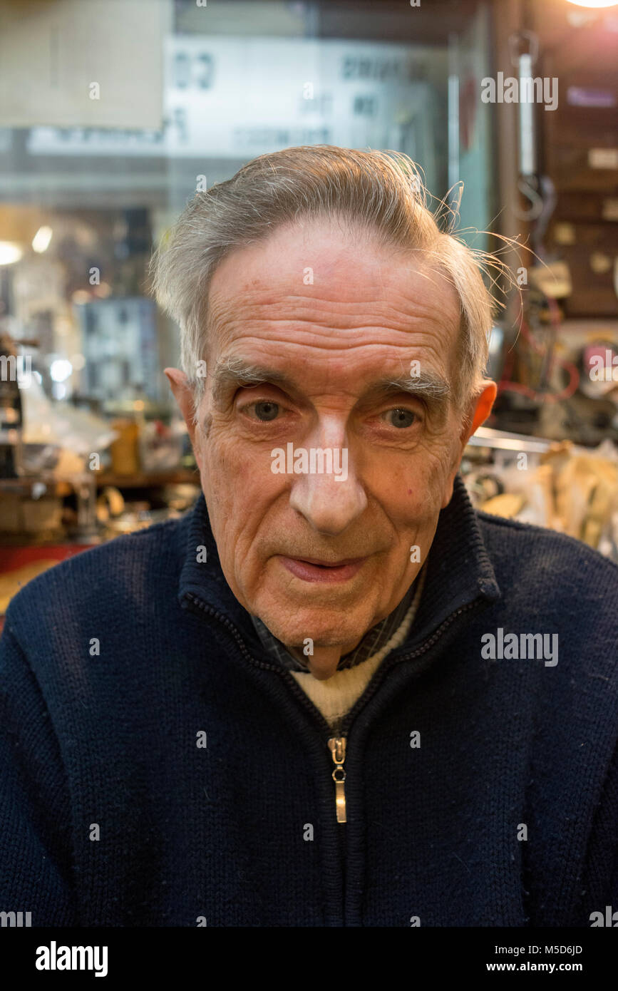 Un vecchio sperimentato riparazione orologi uomo si siede nel suo negozio al suo banco da lavoro Foto Stock