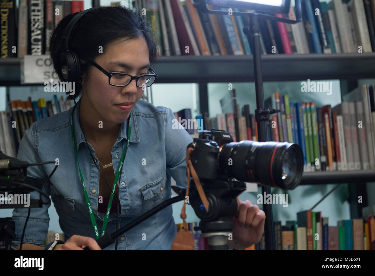 Gli studenti dei college campus prendere parte in modo organizzato un evento sociale nella libreria e sono ripresi per un video online mentre viene intervistato Foto Stock