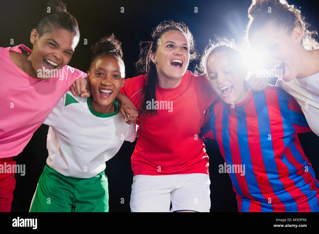 Ritratto entusiasta, fiducioso giovane femmina soccer team il legame e il tifo in huddle Foto Stock