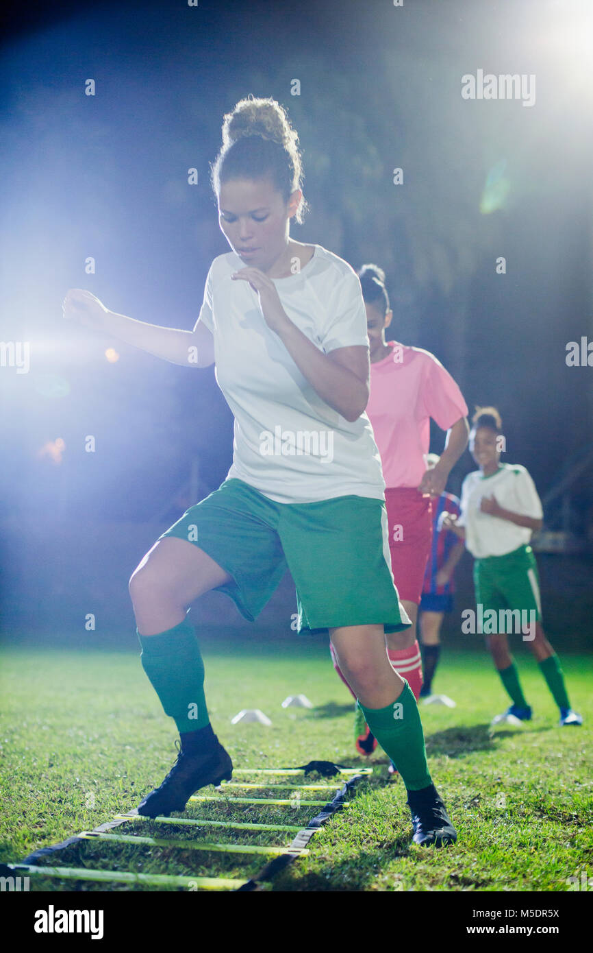 Femmina di giovani calciatori di praticare sport di agilità di praticare sul campo di notte Foto Stock
