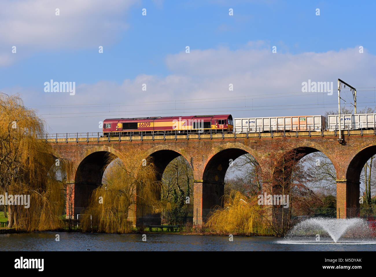Classe DBS 66 elettrica diesel trasporta un treno merci incrocio viadotto ferroviario a Central Park, Chelmsford Essex, linea da Londra Liverpool Street Foto Stock
