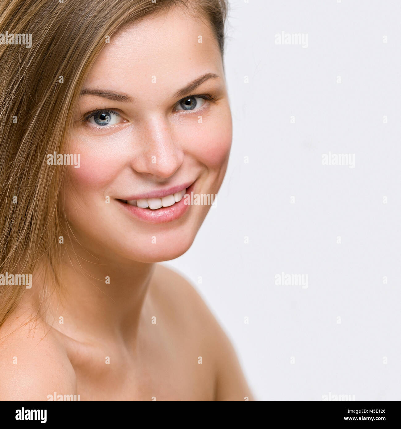 Ritratto di una giovane e bella donna sorridente su sfondo grigio Foto Stock