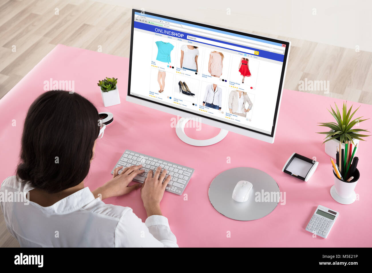Vista posteriore di una imprenditrice Shopping Online con Rosa scrivania in ufficio Foto Stock
