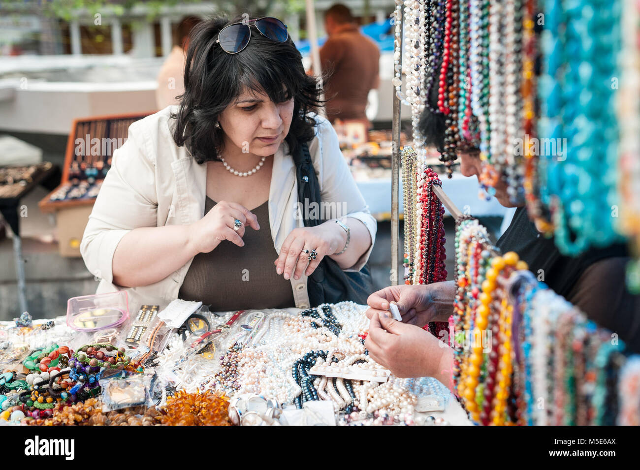 Donna ispezione di artigianato in vendita al vernissage, mercato delle pulci a Yerevan, Armenia. Foto Stock