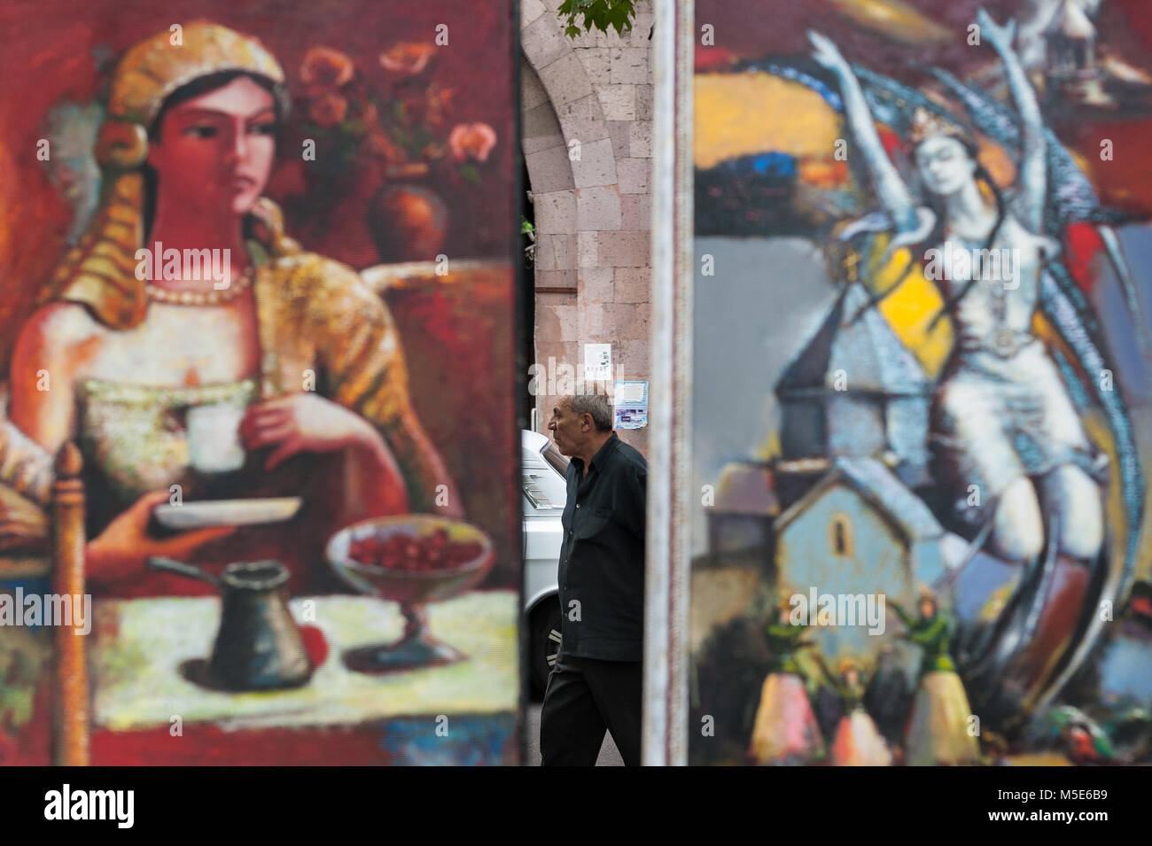 Uomo a camminare tra i due dipinti di Le vernissage il mercato delle pulci a Yerevan, Armenia. Foto Stock