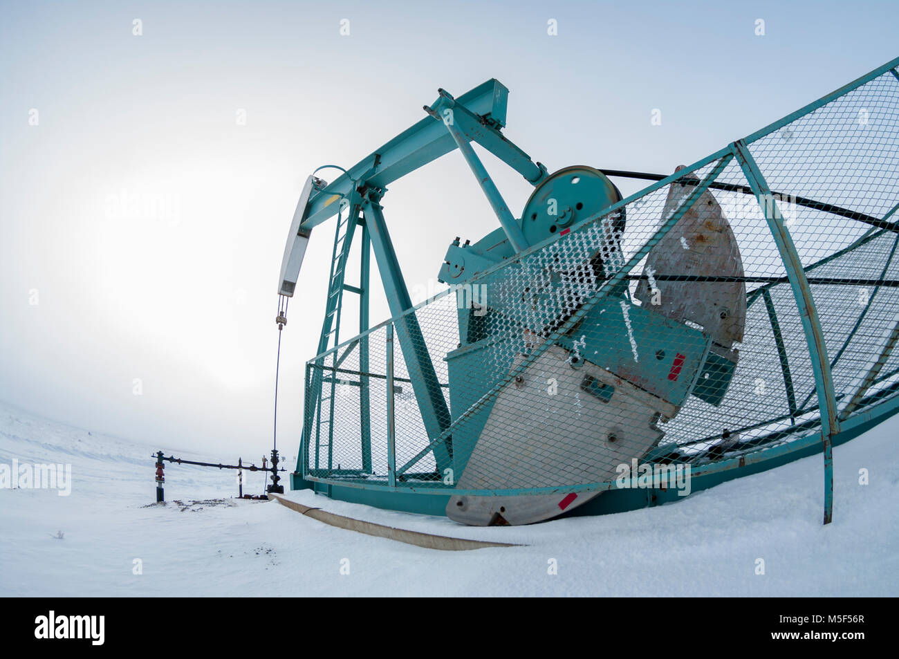 Alberta, Canada. Olio bene pumpjack sulle praterie su un nebbioso giorno in inverno, fisheye prospettiva. Foto Stock