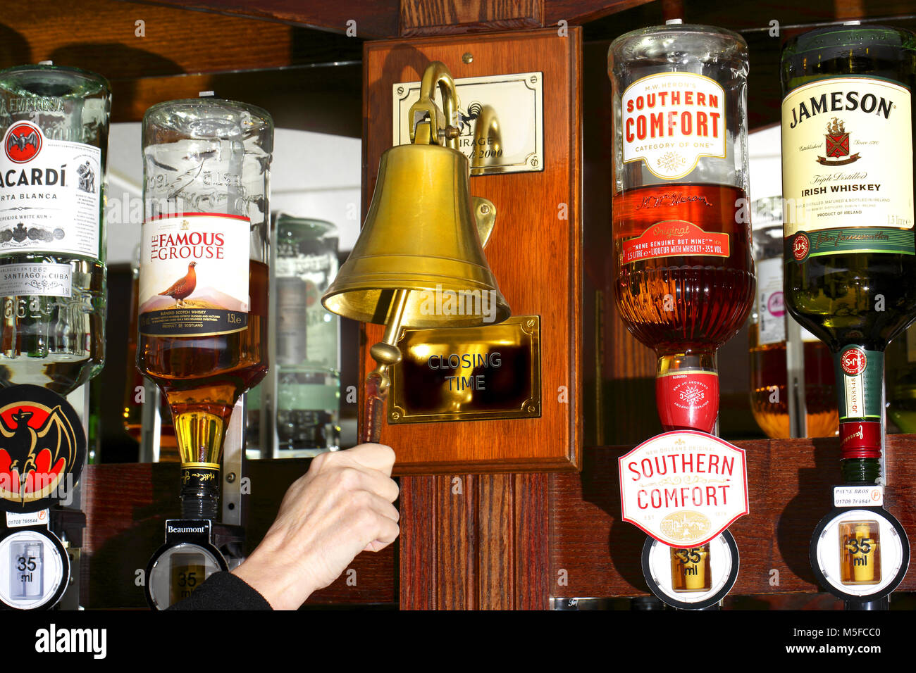'L'orario di chiusura' campana montata fra le bottiglie di alcolici Foto Stock