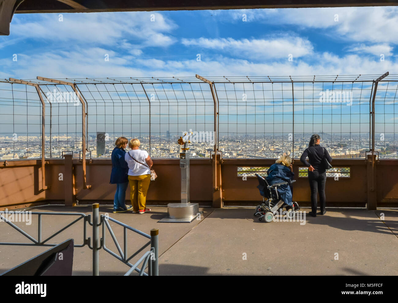 Turisti tra cui una donna su una sedia a rotelle godetevi la vista sulla città di Parigi in una giornata di sole dalla prima piattaforma della Torre Eiffel a Parigi Francia Foto Stock
