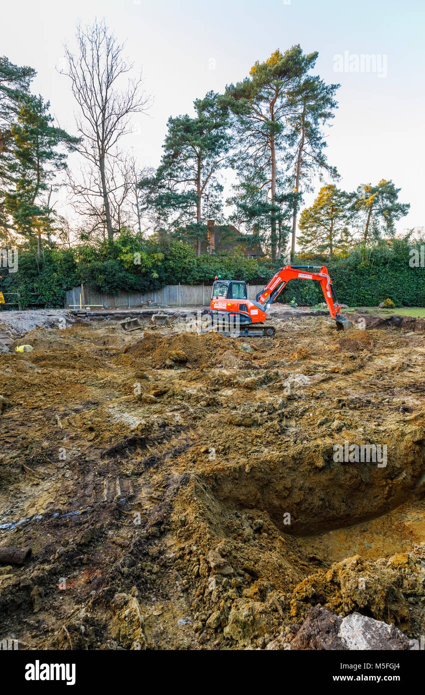 Arance grandi impianti pesanti escavatore meccanico parcheggiato su un cantiere di scavo dopo gli scavi per le fondazioni di un nuovo sviluppo residenziale Foto Stock