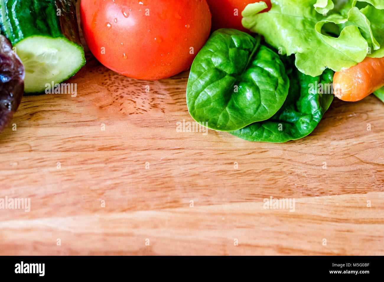 Fresca insalata colorata ingredienti, su tavola di legno, sala per il testo. La lattuga, pomodoro, cetriolo, carota, closeup, camera per copia. Foto Stock