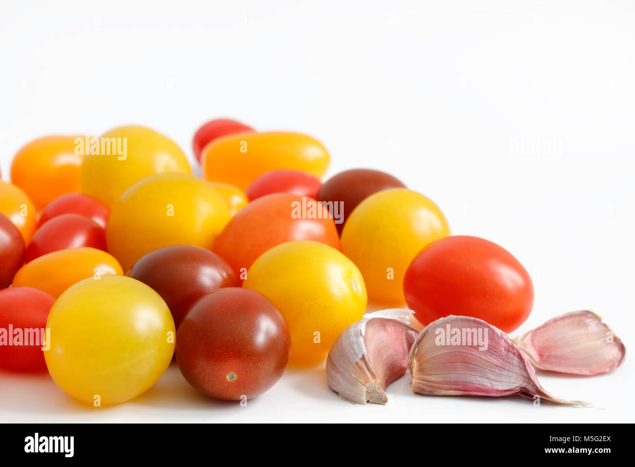 Varietà di prugna, uva, ciliegia, pomodorini con rosso, arancio e giallo colori e spicchi di aglio con copia spazio al top Foto Stock