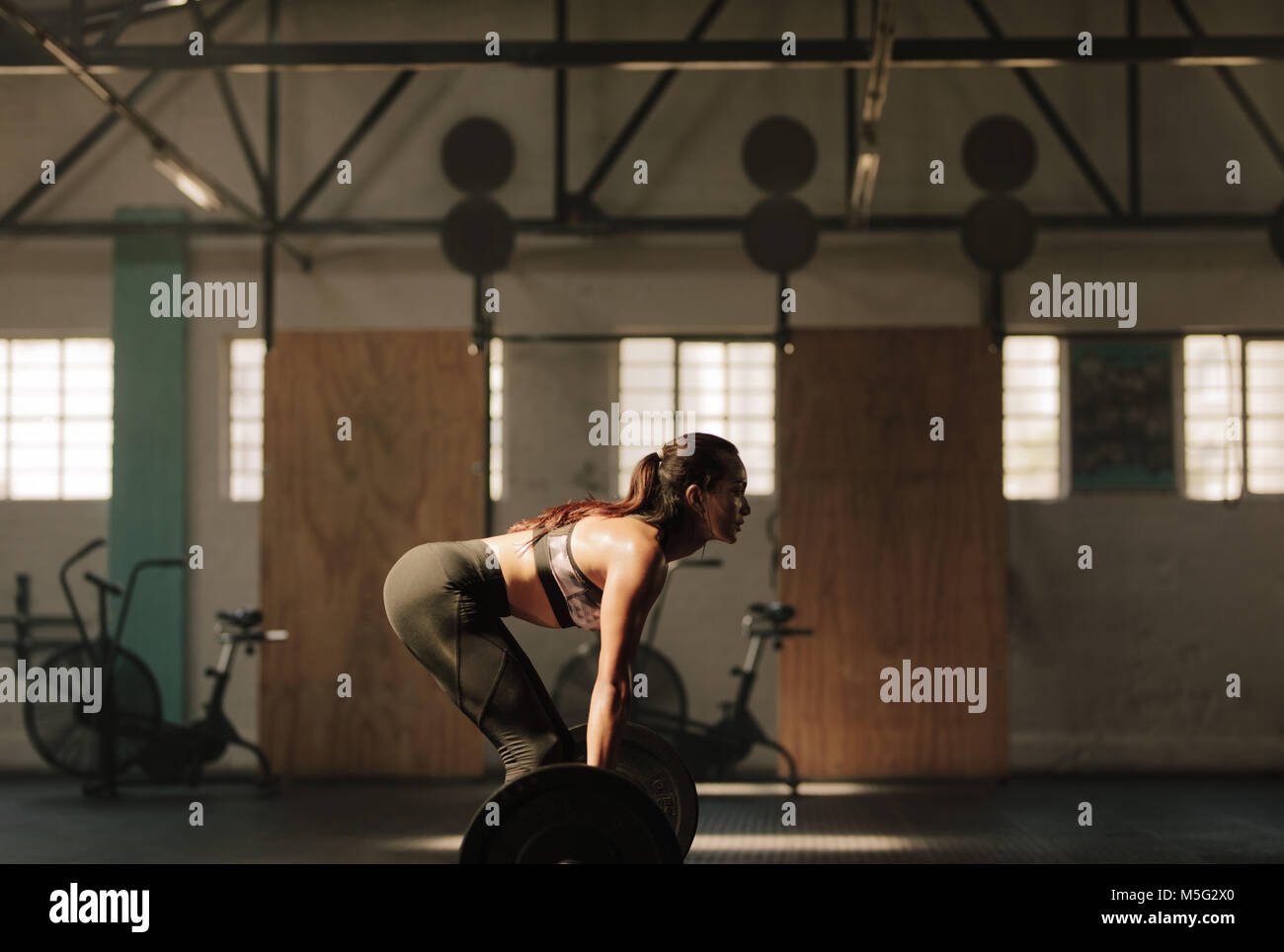 Forte giovane donna di sollevamento pesi pesanti in palestra. Femmina Fitness facendo peso pesante allenamento. Foto Stock