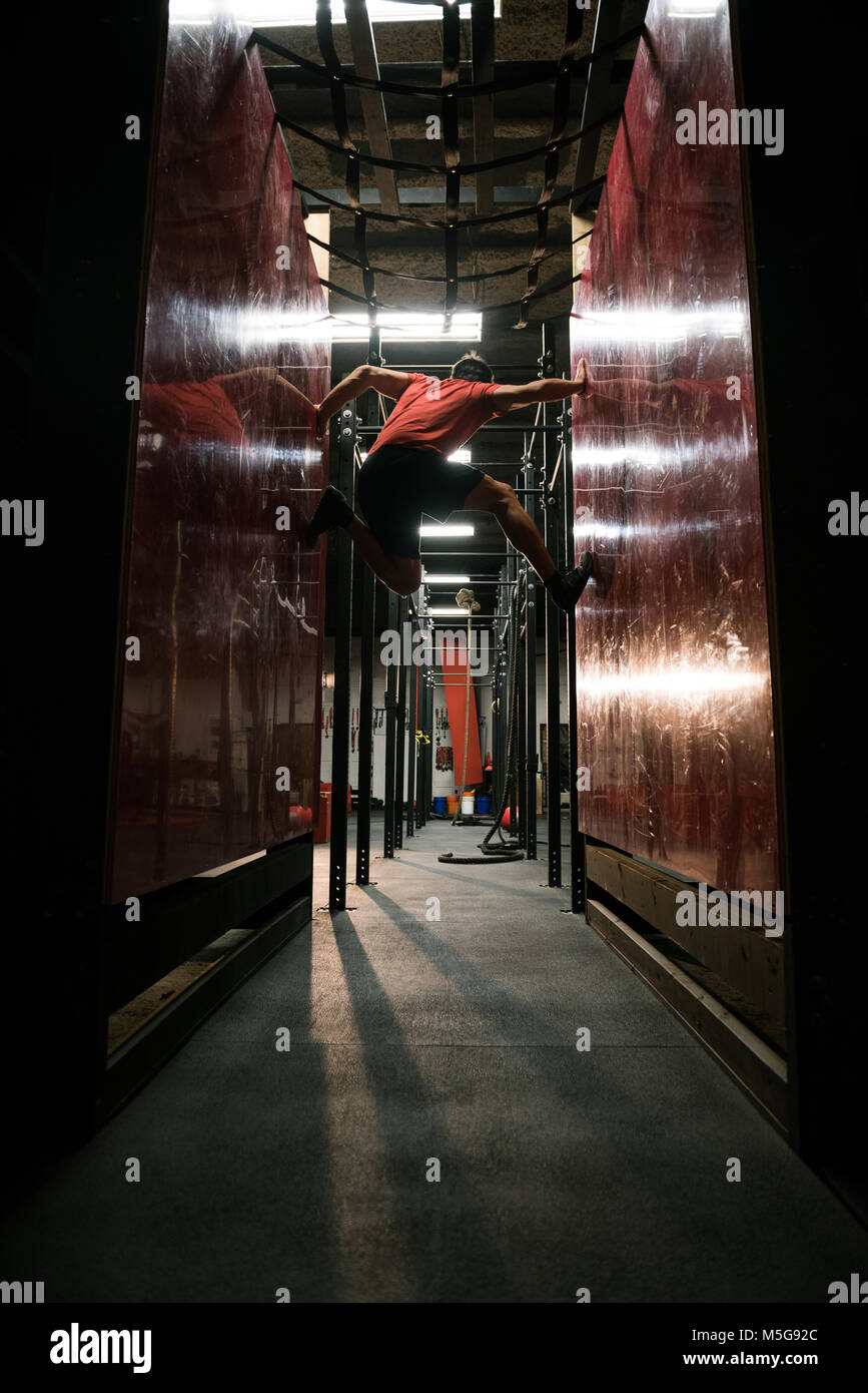 Uomo muscolare arrampicarsi tra due pareti Foto Stock