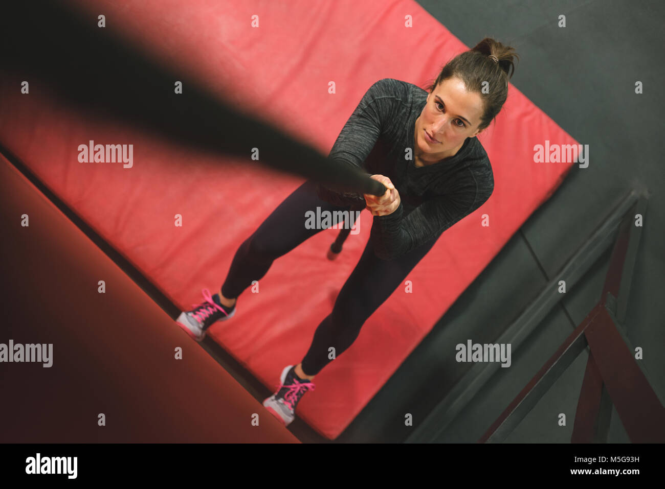 Donna muscolare salendo una parete con corda Foto Stock