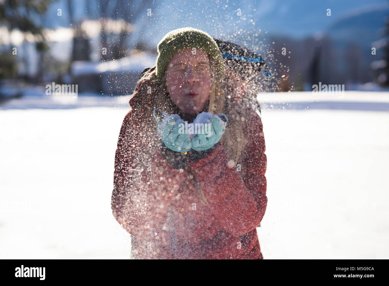 Donna lavori di soffiaggio della neve dalle sue mani in inverno Foto Stock
