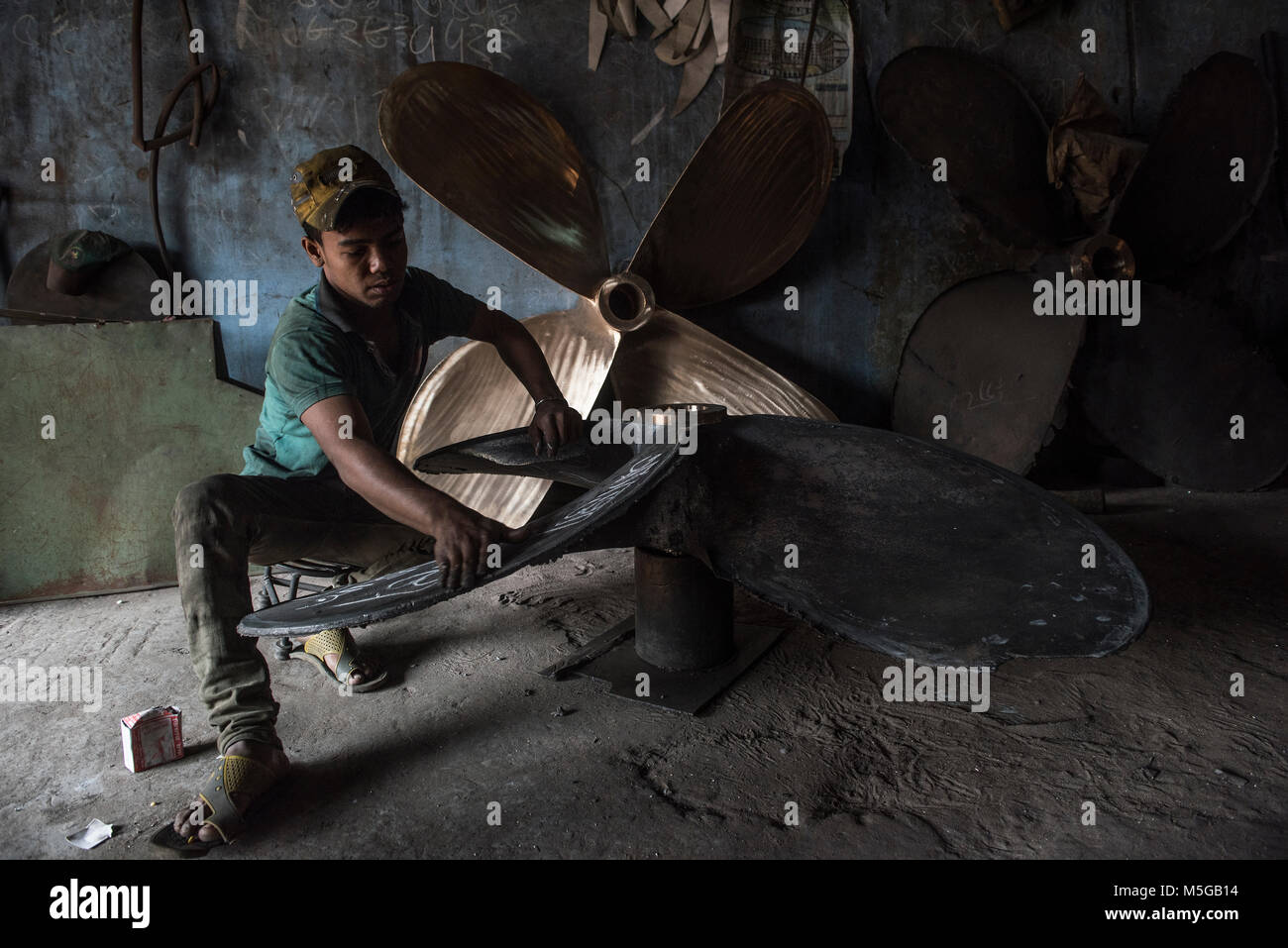 Un giovane ragazzo funziona su un traghetto in fase di ristrutturazione presso un cantiere in Keraniganj, vicino a Dacca in Bangladesh Foto Stock