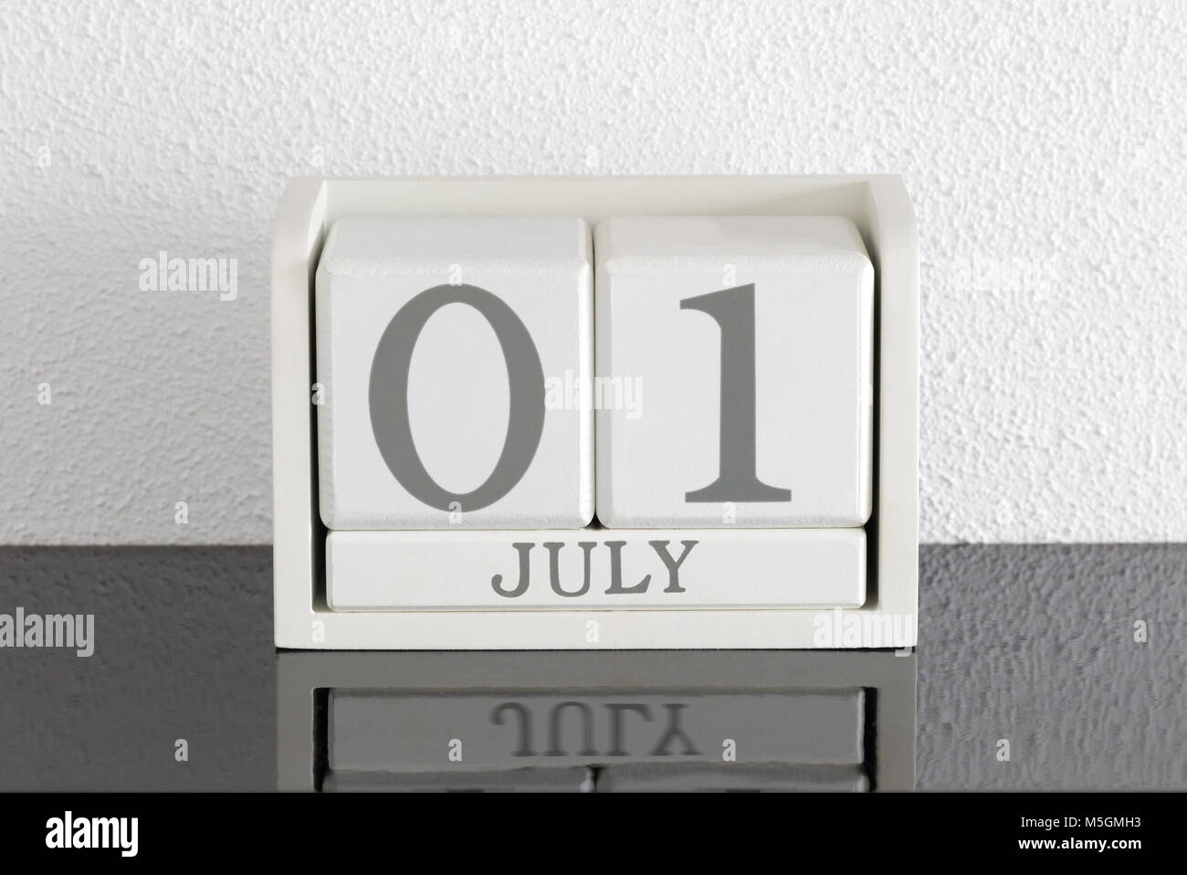 Block Bianco calendario data presente 1 e il mese di luglio sul muro bianco sullo sfondo Foto Stock