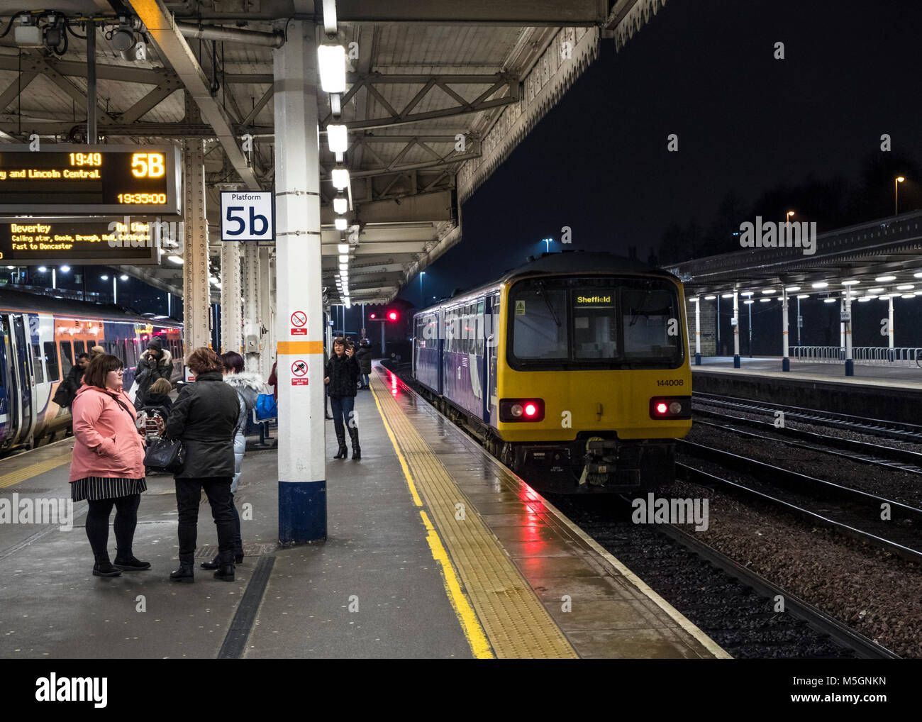 Le persone in attesa di treni su Sheffield Stazione Ferroviaria di notte, England, Regno Unito Foto Stock