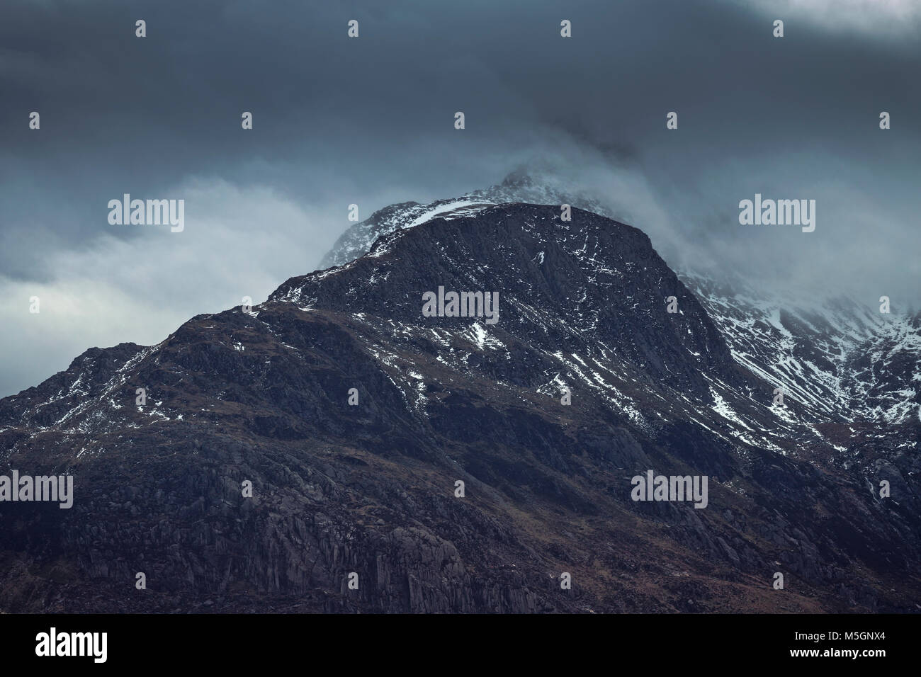 Scenic picco di montagna tappate nella drammatica nuvole all'inverno. Parco Nazionale di Snowdonia nel Galles del Nord, Regno Unito Foto Stock