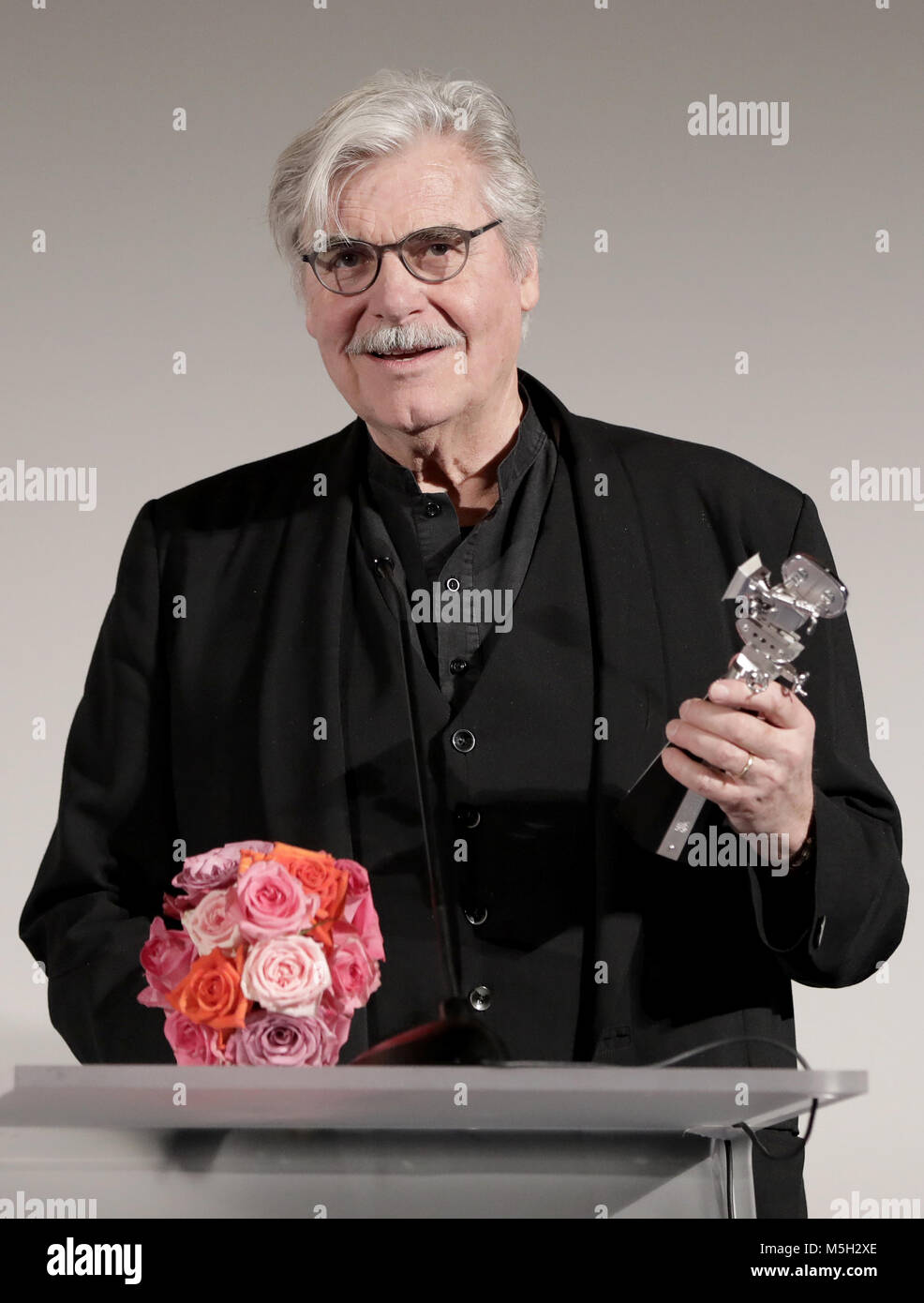 23 febbraio 2018, Germania Berlino - Berlinale, Berlinale Kamera per Jiri Menzel: l'attore Peter Simonischek accetta la Berlinale Kamera e un mazzo di fiori per Jiri Menzel. La Repubblica ceca regista e attore non è stato in grado di ruotare fino a causa di motivi di salute. Foto: Jörg Carstensen/dpa Foto Stock