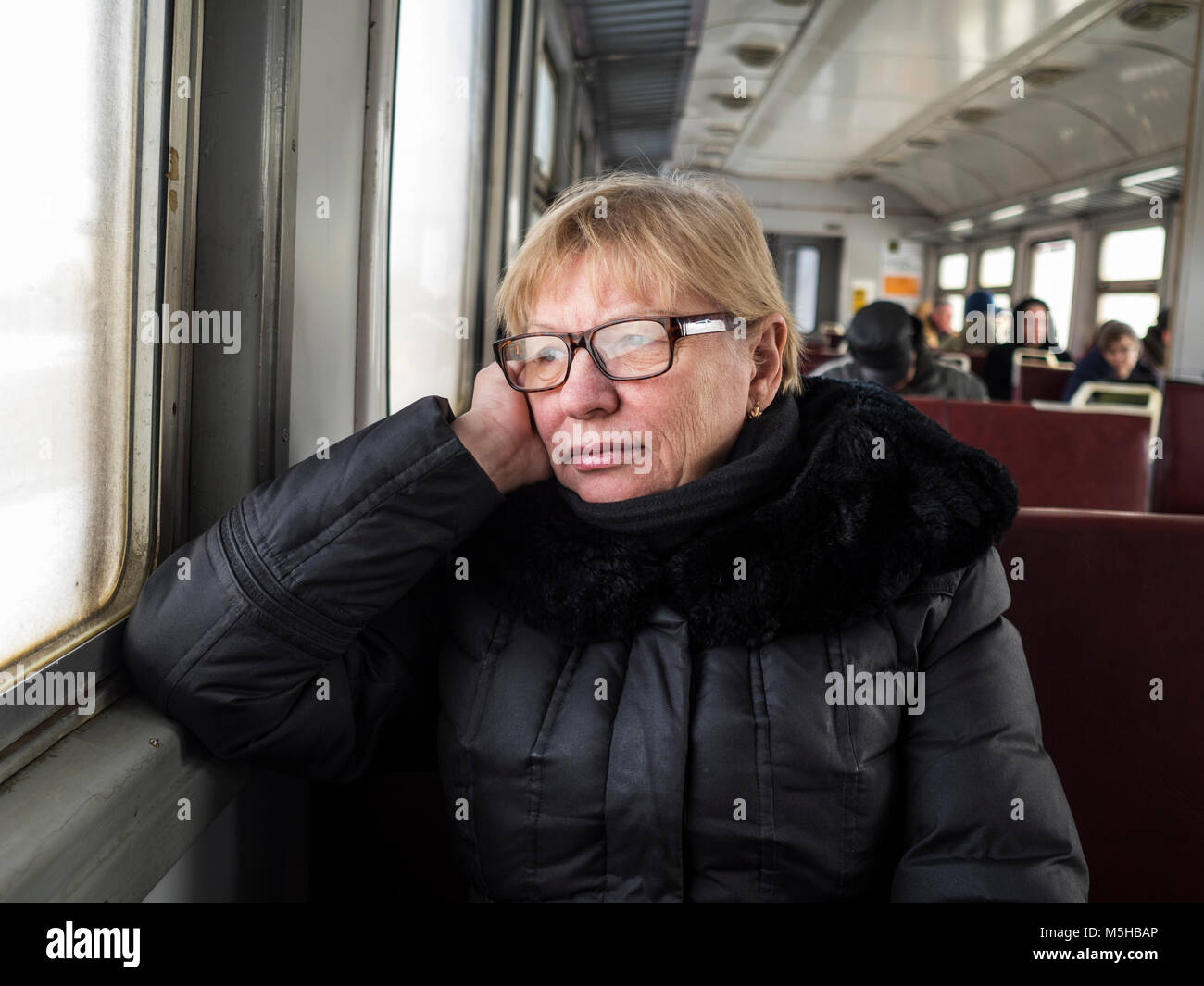Midle invecchiato donna caucasica si siede vicino alla finestra in treno Foto Stock