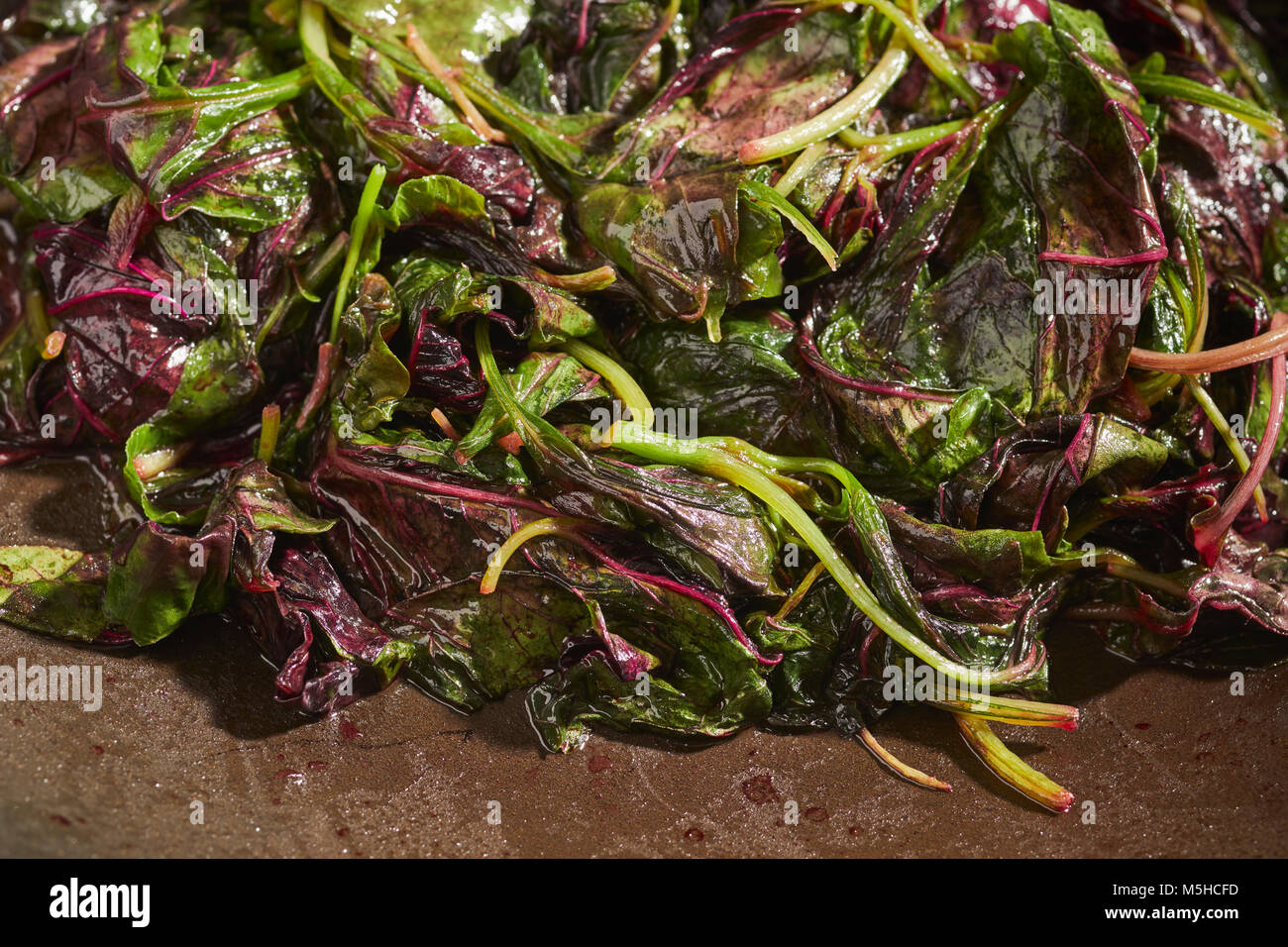 Amaranto Rosso, un tipo di spinaci popolare in asiatica, cotti in un wok Foto Stock