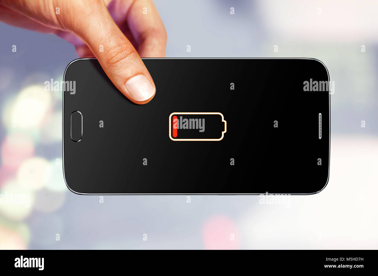 L'uomo detiene il dispositivo mobile che mostra sullo schermo che una batteria è bassa Foto Stock