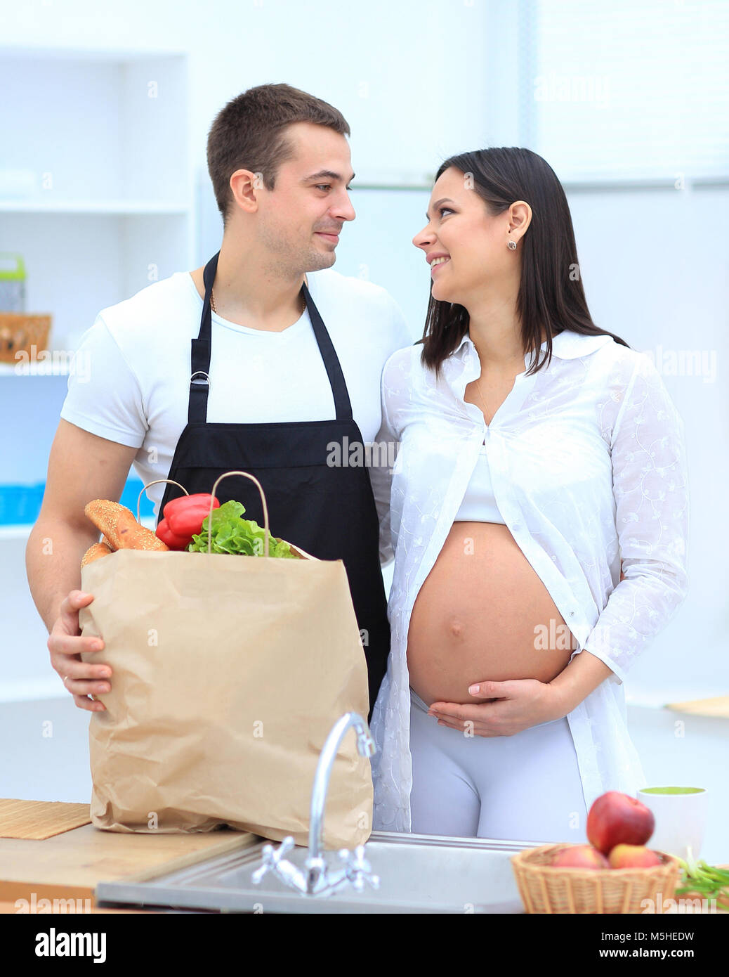 Il marito e la moglie incinta pettinatura sono attraverso il pack,in piedi in cucina Foto Stock