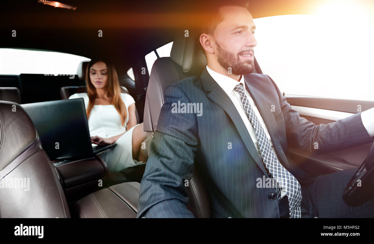 Un uomo aziona un auto e una donna che utilizza un computer portatile e si prepara per una presentazione Foto Stock