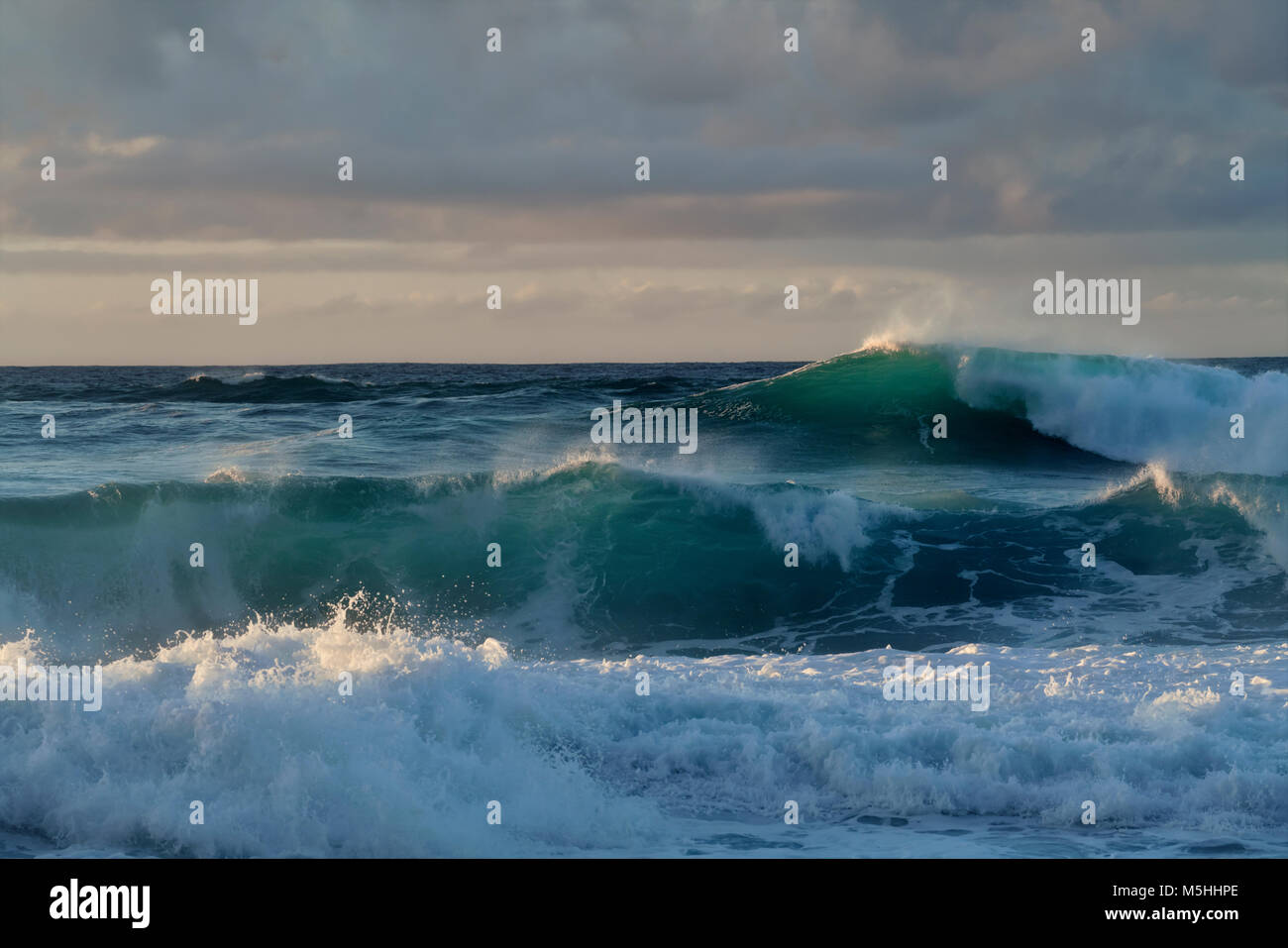 Luce della Sera come grandi onde costruire lungo la North Shore a ke'e sulla spiaggia di Hawaii dell Isola di Kauai. Foto Stock