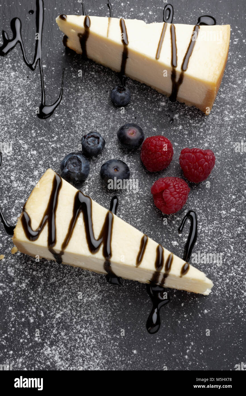 Due Fette Di Cheesecake Con Salsa Alla Liquirizia Mirtilli E Lamponi Su Una Scheda Di Ardesia Foto Stock Alamy