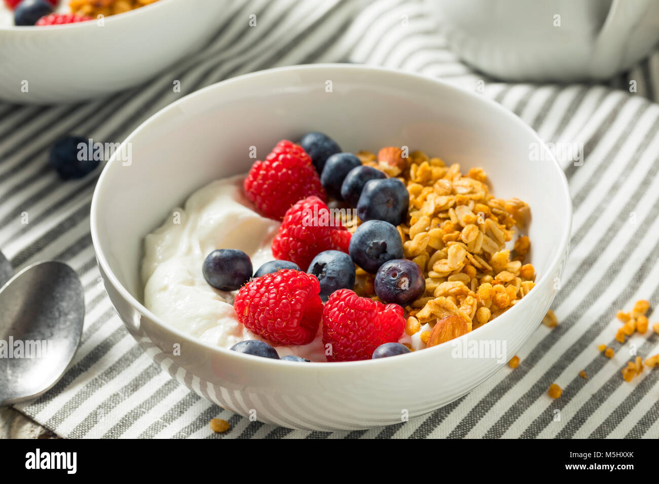 Organico sano lo yogurt greco con cereali e frutti di bosco in una ciotola Foto Stock