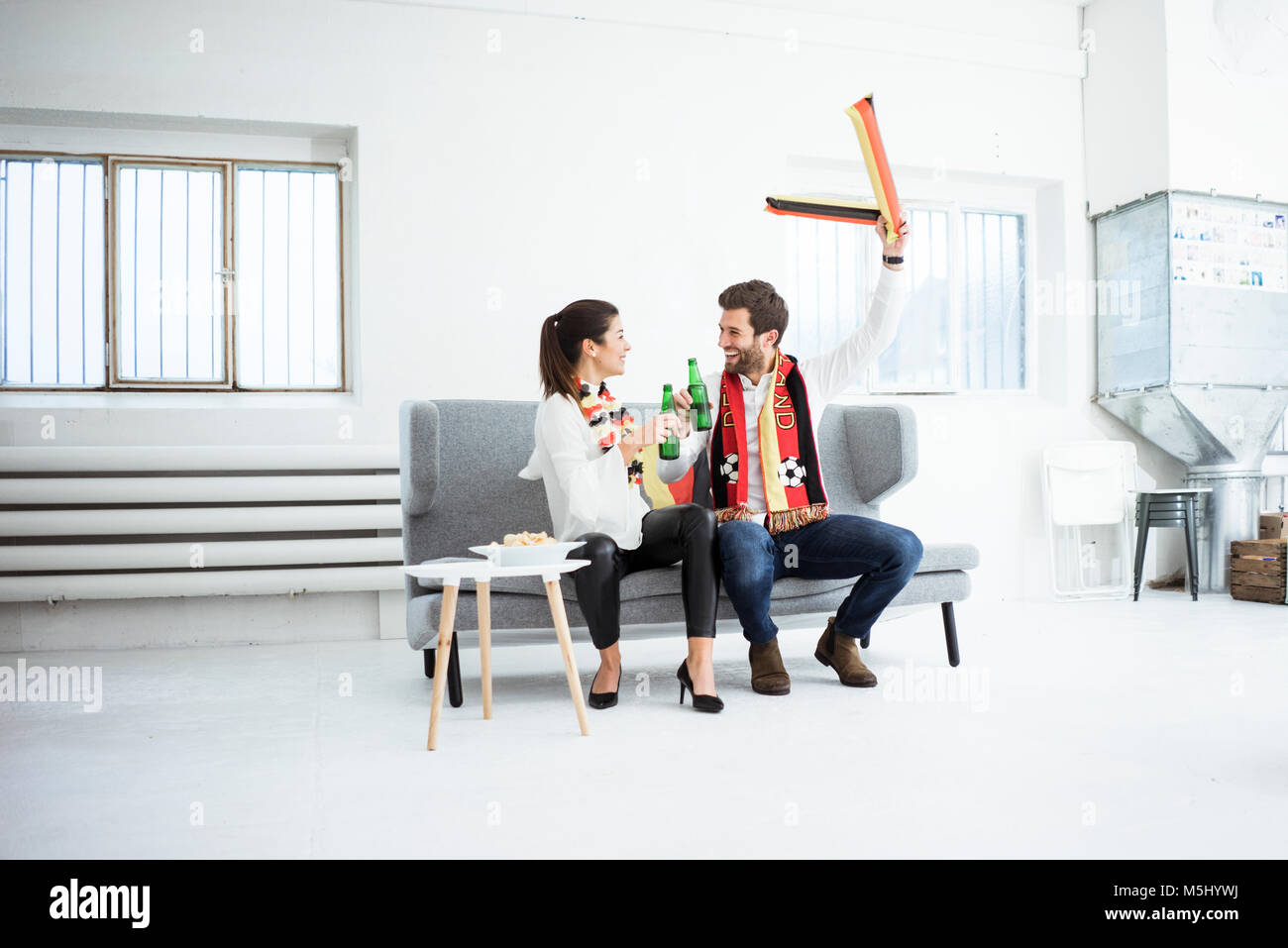 Felice tedesco appassionato di calcio giovane seduto sul lettino Foto Stock